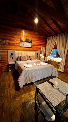 a bedroom with a large bed in a wooden room at Cabana Alpen Ville Rural com Banheira in Bom Jardim da Serra
