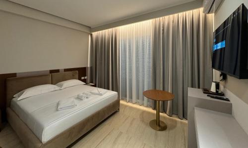 a bedroom with a bed and a television and a table at Anchor Luxury Rooms in Vlorë