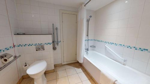 a bathroom with a toilet and a tub and a sink at Holiday Inn Brentwood by IHG in Brentwood