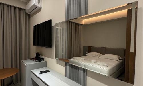 a bedroom with a bed with a mirror and a television at Anchor Luxury Rooms in Vlorë