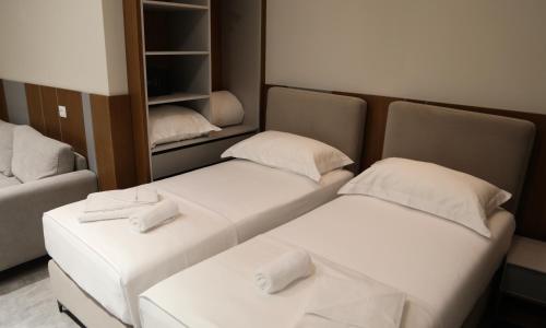 two beds in a small room with a closet at Anchor Luxury Rooms in Vlorë
