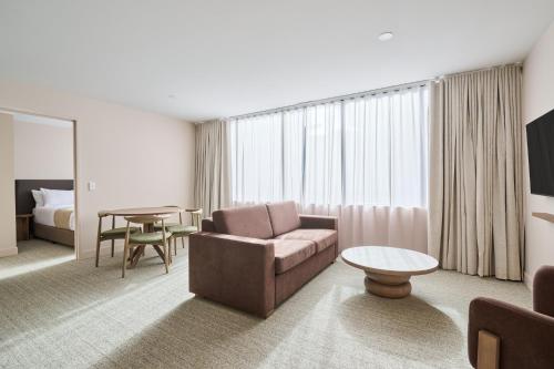 Habitación de hotel con sofá y mesa en Abode Phillip, en Canberra