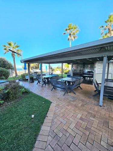 a patio with picnic tables and palm trees at 19th Avenue on the Beach in Gold Coast