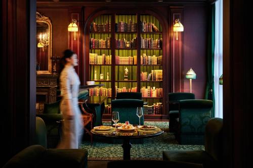 a woman walking through a library with a table and books at L'Escape Hotel in Seoul