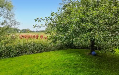 a tree in a field with a herd of cows at Nice Home In Drochtersen in Drochtersen