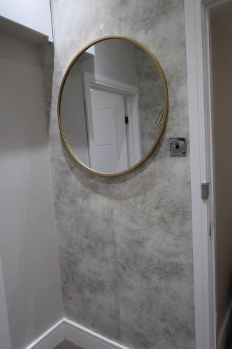 a round mirror on a wall in a bathroom at Quaint Retreat In The Historic District Local in Sherborne