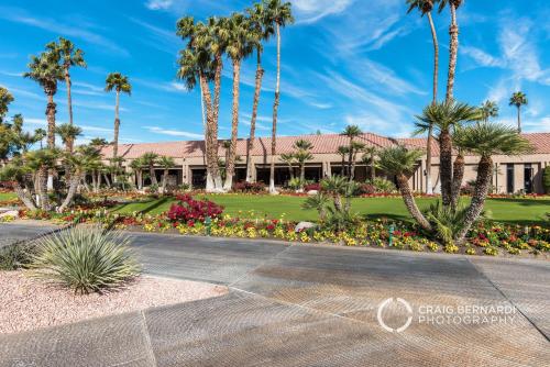 a building with palm trees and flowers in a park at Desert Country Club Paradise! in Cathedral City