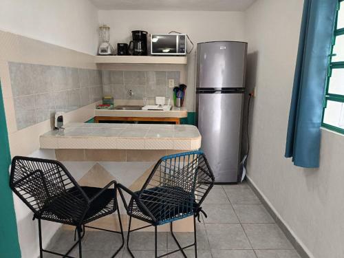a kitchen with two chairs and a refrigerator at Studios Yaxkin, located in downtown in Cozumel