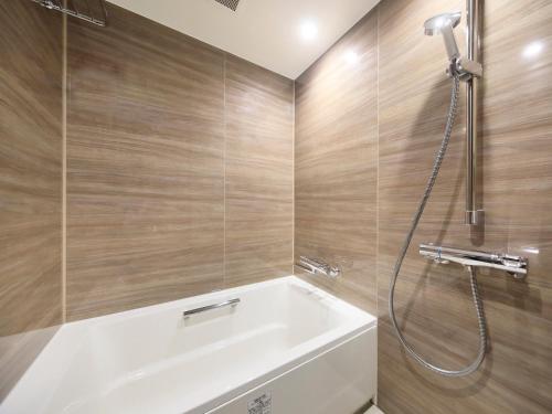 a bathroom with a white tub and a shower at QuintessaHotel FukuokaHakata Relax&Sleep in Fukuoka