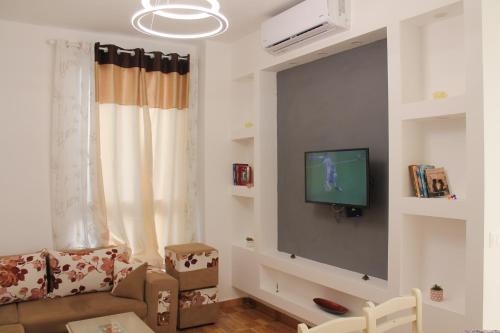 a living room with a couch and a tv on a wall at Holiday Gateway in Shëngjin