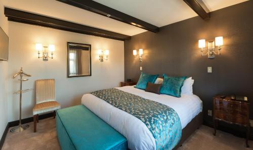 a bedroom with a large bed and a chair at Scenic Hotel Cotswold in Christchurch