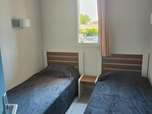 deux lits dans une petite pièce avec une fenêtre dans l'établissement Appartement Bord de Mer - Climatisation, Balcon, Parking et Piscine - FR-1-801-3, au Cap d'Agde