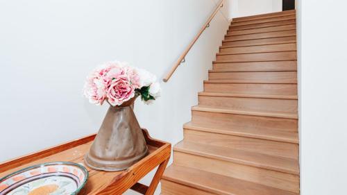 a vase with flowers on a table next to a staircase at Bellas Block in Shoreham