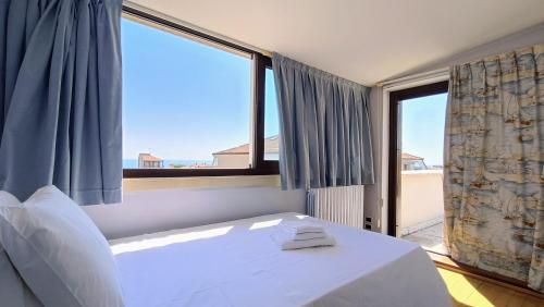 a bedroom with a bed and a large window at Attico Novecento in Porto San Giorgio