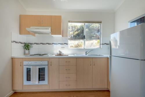 a kitchen with wooden cabinets and a white refrigerator at BIG 4 Tasman Holiday Parks - Ledge Point in Ledge Point
