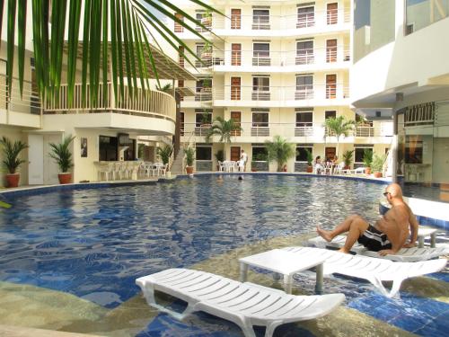 アンヘレスにあるKANDI B11, Poolside, Free Netflix, 250 MBPS, 55" Smart TV, Deluxe King Bed, Fully Equipped Kitchen, Electric is Xtraの建物の隣にあるプールの椅子に座っている男性