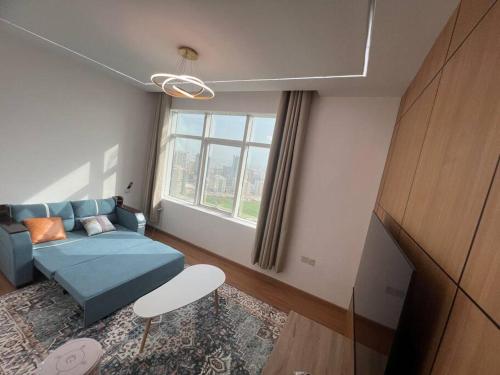 アジュマーンにあるElite Horizon Ajman Residenceの青いソファと窓のあるリビングルーム