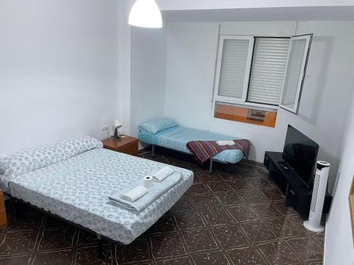 a bedroom with two beds and a flat screen tv at Habitación grande y comoda en piso particular y familiar in Valencia