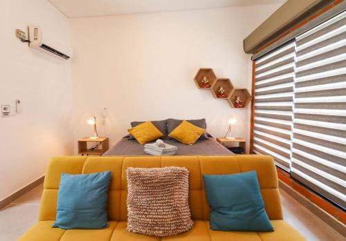 a bedroom with a yellow couch with blue pillows at Apartamento amoblado en Carepa cerca al aeropuerto in Carepa