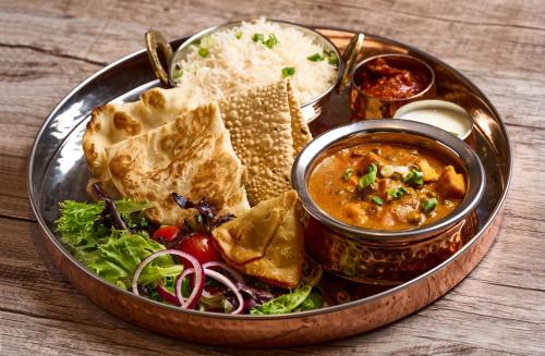 a plate of food with nepalese food on a table at Holiday Inn Golden Mile by IHG in Hong Kong