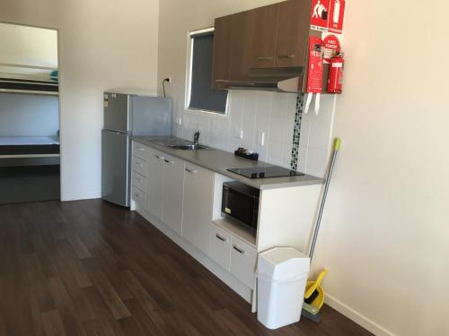a kitchen with a stove, microwave and refrigerator at Jervis Bay Holiday Cabins in Sussex Inlet