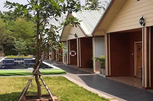 a tripod in front of a house with a tree at Phenwaree Amphawa Resort in Ban Dao Dong