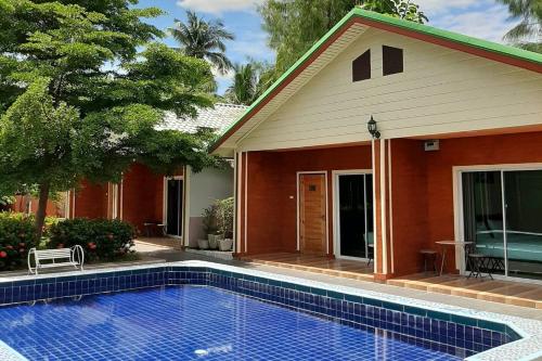 a house with a swimming pool in front of a house at Phenwaree Amphawa Resort in Ban Dao Dong