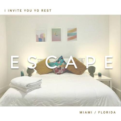 a bedroom with a white bed with the word escape at GroveO5 10 minutes from Miami Beach in Miami