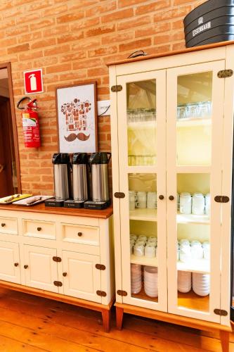 a white cabinet with dishes inside of it at Pousada Santa Felicidade in Campos do Jordão