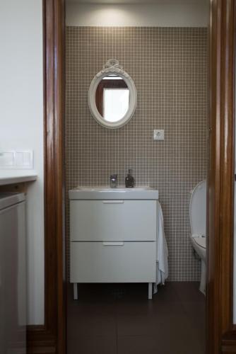 a bathroom with a sink and a mirror and a toilet at Nidos Accommodation Gaia in Vila Nova de Gaia