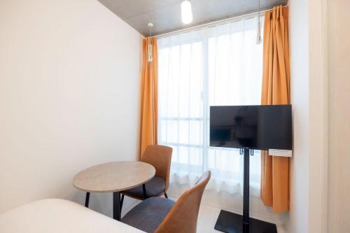 a room with a bed and a table and a tv at ARUCIA Sangenjaya in Tokyo