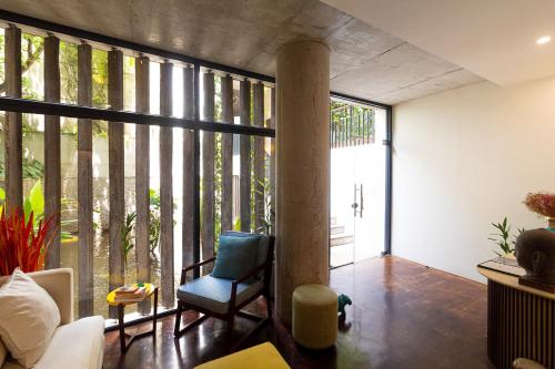 a living room with a chair and a large window at Penh House Hotel in Phnom Penh