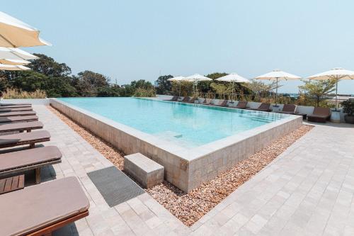 a swimming pool with chairs and umbrellas at Penh House Hotel in Phnom Penh