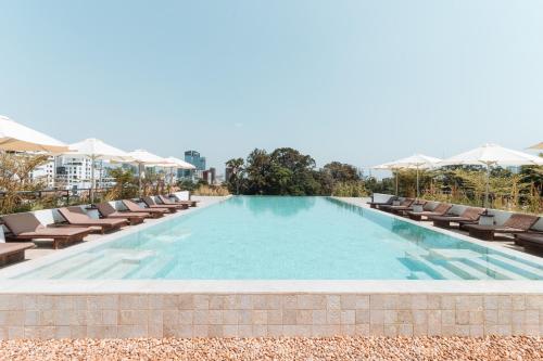 a large swimming pool with lounge chairs and umbrellas at Penh House Hotel in Phnom Penh
