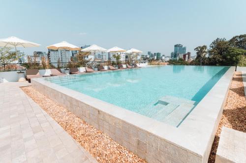 a swimming pool with chairs and umbrellas at a resort at Penh House Hotel in Phnom Penh