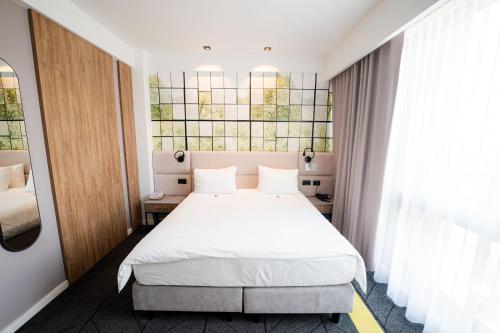 a bedroom with a white bed and a window at Mandachi Hotel & SPA in Suceava