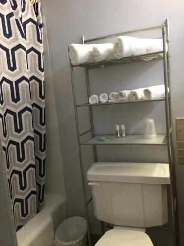 a bathroom with a toilet and a shower with towels at Swiss Cottage Inn in Niagara Falls