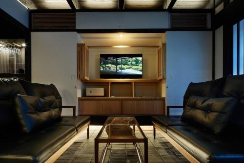 a living room with two leather couches and a tv at 季楽 京都 凛葩 Kiraku Kyoto Rinpa in Kyoto