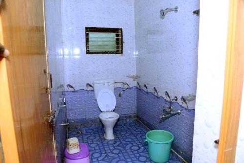 a bathroom with a toilet in a blue tiled bathroom at SRI RANGA RESIDENCY in Māvingundi