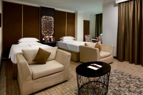 a hotel room with a bed and two chairs and a table at Palace Gate Hotel & Resort By EHM in Phnom Penh