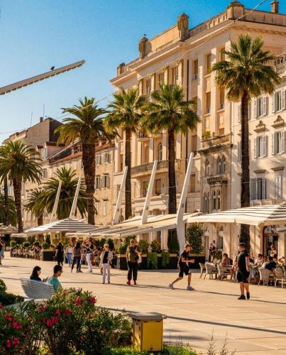 a group of people walking in a plaza with white umbrellas at Calma Luxury Rooms in Split