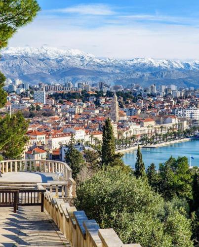 a view of a city with snow covered mountains at Calma Luxury Rooms in Split