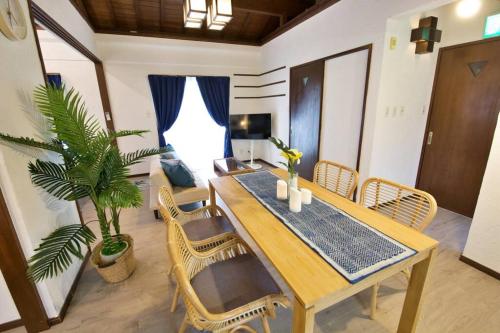 a dining room with a wooden table and chairs at 崎本部戸建プール付き g棟 in Motobu