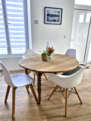 une table en bois avec des chaises blanches et une table avec des fleurs. dans l'établissement La Capucine, à Coulommiers