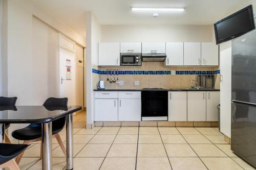 a small kitchen with white cabinets and a table at ATKV Natalia in Kingsburgh