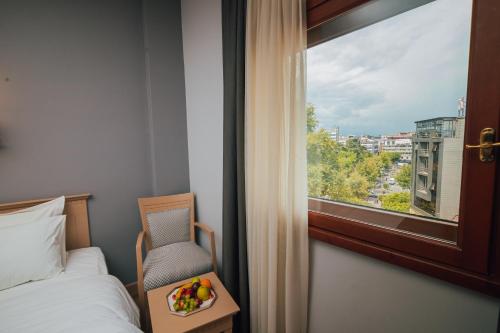 een slaapkamer met een bed, een stoel en een raam bij Usta Park Hotel in Trabzon