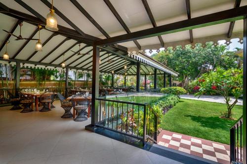 an outdoor patio with tables and chairs and a garden at De Mandarin Beach Resort Suites & Villas, Candolim in Candolim
