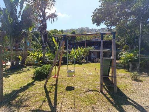 a swing set in a yard with a house at Villa Baies Roses in Saint-Leu