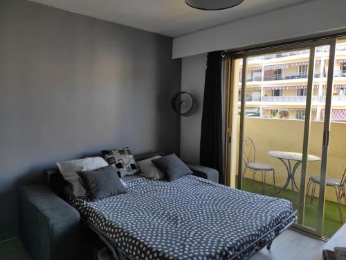 une chambre avec un lit et un balcon avec une table dans l'établissement Très joli studio,bien équipé terrasse,internet, au Cannet