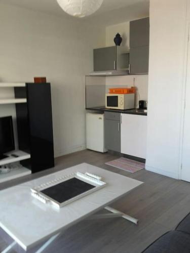 - une cuisine avec une table blanche dans une pièce dans l'établissement Très joli studio,bien équipé terrasse,internet, au Cannet